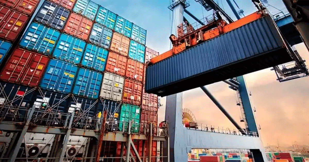 Stacked shipping containers at a North American port terminal with crane loading cargo.